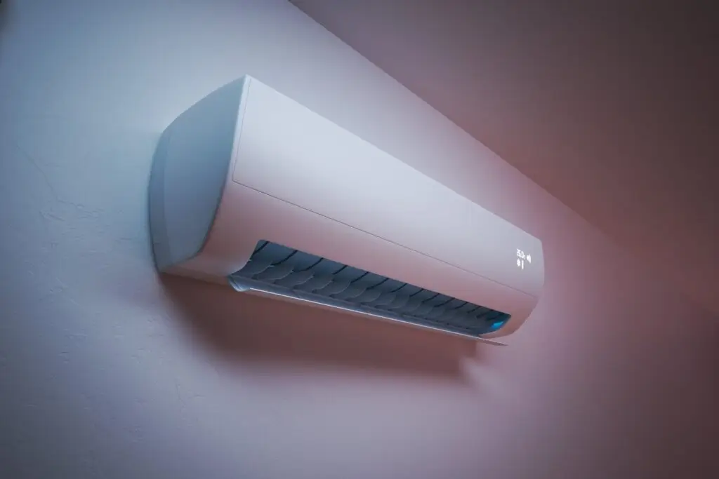 A modern wall-mounted air conditioner unit with a digital display showing the temperature, installed on a light-colored wall.