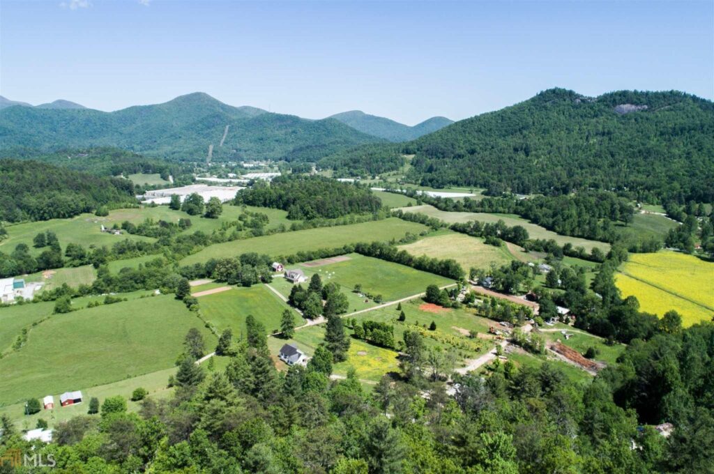 Aerial view of green farmland, forests, and mountains during daytime.